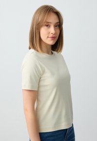 Crème kleurige t-shirt met korte mouwen en een ronde halslijn, gemaakt van een gladde stof, met een strakke pasvorm en nette stikdetails.