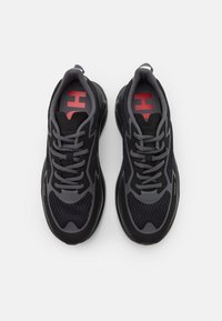 Sneaker sportive in nero e grigio con texture in rete, lacci e un logo rosso prominente sulle sole. Suola curva che offre ammortizzazione.