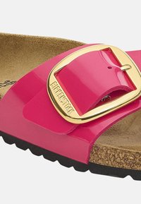 Sandalo in pelle verniciata rosa con una fascia larga, dotato di una fibbia dorata e di una soletta in sughero. La suola in gomma nera texturizzata offre aderenza.