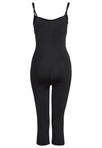 Jumpsuit noir en matériau extensible, avec de fines bretelles et un design ajusté, s'étendant jusqu'à mi-mollet.
