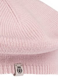 Soft pink knitted beanie hat with a folded brim and a small beige tag featuring a black crest logo.