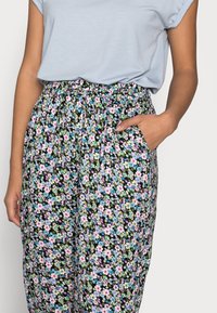 Blommiga byxor med svart bakgrund, prydda med färgglada små blommor i rosa, blått och grönt. Har resår i midjan och sidofickor.