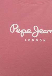 Rosa ribbatts tyg T-shirt med texten "Pepe Jeans LONDON" i vita kursiverade bokstäver över bröstet.