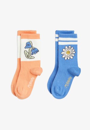 Calcetines naranjas y blancos con bordado de flores azules; calcetines azules con rayas blancas que presentan un diseño de margaritas. Ambos están hechos de un material suave.