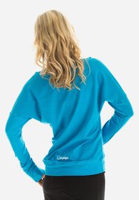 Light blue sweatshirt with a relaxed fit, long sleeves, and a rounded back hem. Features a white brand logo at the lower left side.
