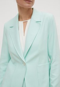 Licht mintgroene blazer met notch-revers, voorzakken en een enkele knoopsluiting. Glad stoffen textuur, getailleerde pasvorm.