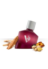 Botella de perfume de vidrio púrpura con tapa plateada, con estrías verticales y un logo blanco "bb", rodeada de madera, jengibre y hierbas aromáticas.