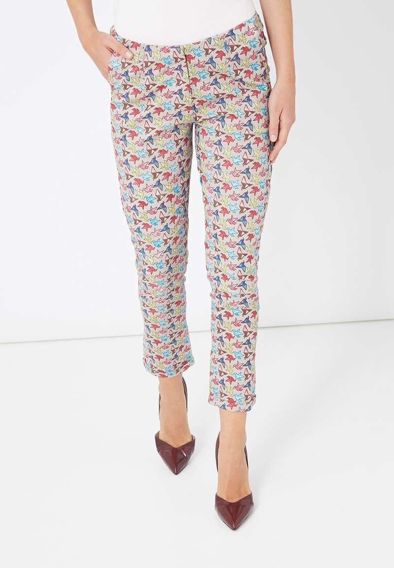 Pantalones impresos coloridos con un patrón de hojas en verde, rojo y azul sobre un fondo claro, con un corte ajustado y puños enrollados.