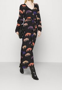 Svart lång klänning med djurmönster i orange, lila och rosa. Har V-ringning, långa ärmar och en figurnära midja med ett band.