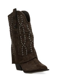 Botín de ante marrón hasta el tobillo con punta afilada, adornado con tachuelas metálicas en un patrón ondulado, con tacón apilado y una tira de sujeción.