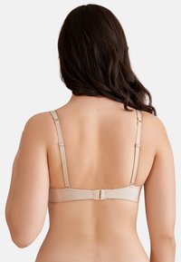 Reggiseno beige con spalline regolabili, texture liscia e chiusura con gancetto sulla schiena. Design semplice senza motivi o accenti visibili.