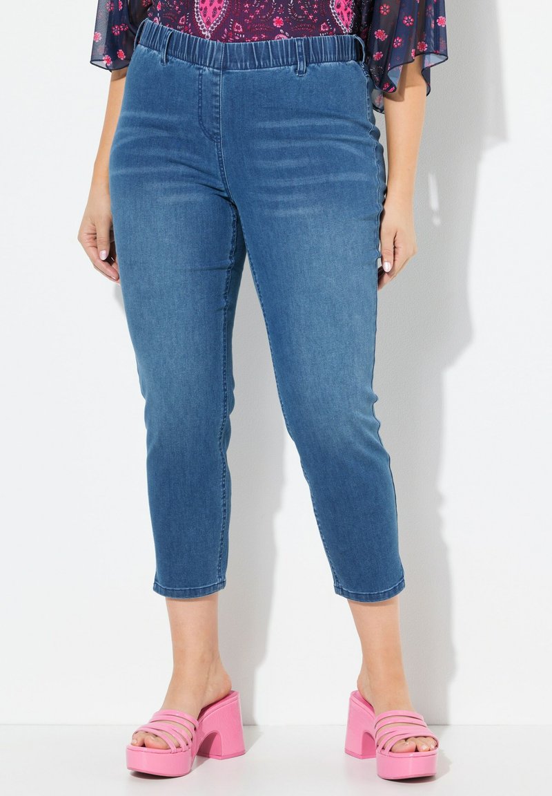 Farkkutrikoot, joissa on joustava vyötärö, vaaleansininen sävy ja slim fit -leikkaus. Yhdistettynä vaaleanpunaisiin paksupohjaisiin sandaaleihin.