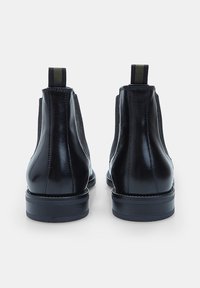 Botas de tobillo de cuero negro con un acabado liso, paneles laterales elásticos y una lengüeta, que cuentan con una suela de goma negra resistente.