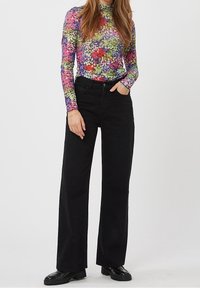 Långärmad, flerfärgad blommig topp med hög hals, kombinerad med svart högmidjade vida jeans och svarta platåskor.