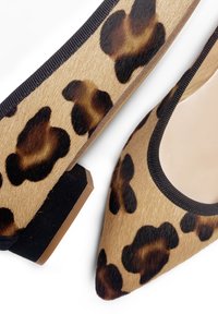Scarpe flat con stampa leopardata e punta affusolata, con una parte superiore beige texturizzata, dettagli neri e un tacco basso nero.