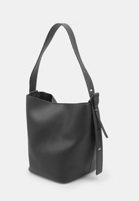 Borsa a secchiello nera in pelle con superficie texturizzata, ampia tracolla e dettagli hardware regolabili. Design minimalista con apertura superiore.