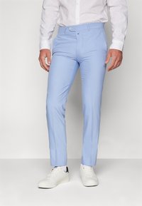 Svetlomodré nohavice so slim fit strihom, s hladkou textúrou, gombíkovým zapínaním a elegantným dizajnom, skombinované s bielymi teniskami.