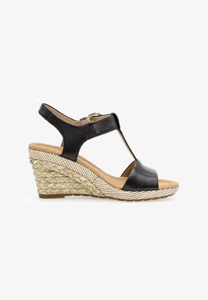 Zwarte lederen wedge sandaal met een geweven rieten design. Voorzien van een T-band en een verstelbare enkelgesp. Zacht beige voetbed.