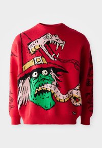 Suéter de punto rojo con un gran gráfico de una bruja de piel verde con una serpiente, detallado con acentos en negro y rosa, diseño de cuello redondo.