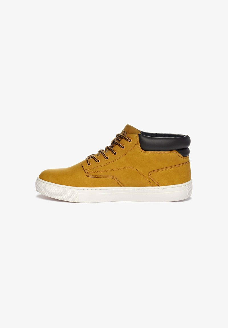 Sneaker alta in pelle beige con colletto imbottito nero, lacci marroni e suola in gomma bianca, caratterizzata da accenti di cucitura e da una texture liscia.
