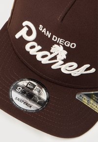 Brown snapback cap featuring "San Diego Padres" embroidered in white, with palm tree graphics and a rounded brim. Includes brand tags.
