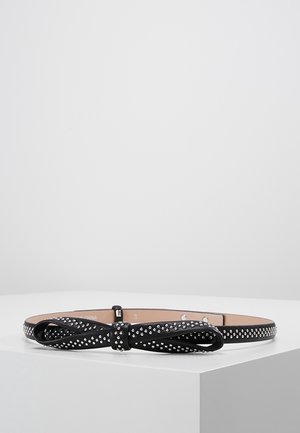 Czarny cienki pasek z ozdobną kokardą i małymi srebrnymi ćwiekami równomiernie rozmieszczonymi na całej długości, wyeksponowany na białym tle.