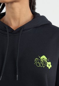 Black hoodie with drawstring, featuring a neon green graphic of a jellyfish, cherries, and a flower on the chest. Soft material, casual design.