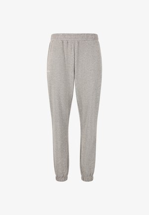 Grijze hoodie en bijpassende sweatpants van zacht materiaal, met een relaxte pasvorm en ribbels aan de mouwen, gecombineerd met zwarte sportschoenen.