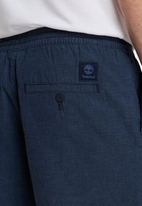 Námořnické modré šortky vyrobené z texturované tkaniny, s elastickým páskem a zadní kapsou s knoflíkem. Viditelná nášivka loga Timberland.
