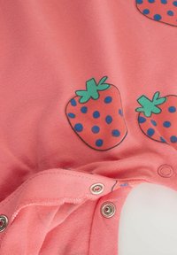 Tissu corail au toucher lisse présentant un motif de fraises avec des feuilles vertes et des pois bleus ; fermetures à snap en bas.