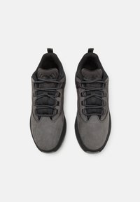 Chaussures de randonnée grises avec une tige en daim texturé, un col rembourré noir, et une fermeture à lacets avec des lacets gris foncé ainsi qu'un embout renforcé.
