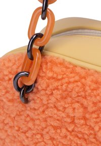 Orange tekstureret stofhåndtaske med en gul lædertop, der har en klumpet kæde-rem i fersken- og sorte led. Lynlås lukning synlig.