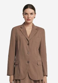 Brązowa, dopasowana marynarka z klapami, dwoma przednimi kieszeniami, trzema guzikami i lekką teksturą materiału. Prosty i nowoczesny design.