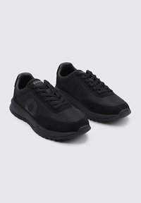 Zapatillas deportivas negras que combinan materiales de malla y ante, con diseño de cordones, cuello acolchado y suela de goma texturizada.