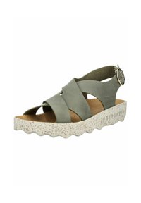 Zelené semišové sandály na klínu s křížovými popruhy, strukturovanou světlejší podrážkou a kulatou kovovou sponou na pásku kolem kotníku. Detail s vykrojeným okrajem.