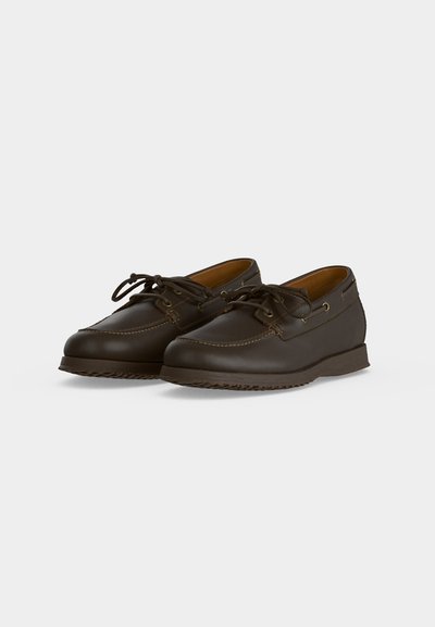 Chaussures bateau en cuir marron foncé avec fermeture à lacets et coutures détaillées, présentées sur un fond clair uni.