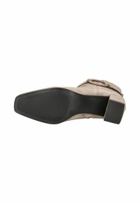 Bota de ante taupe hasta el tobillo con un tacón cuadrado negro y suela texturizada, vista desde abajo contra un fondo blanco.