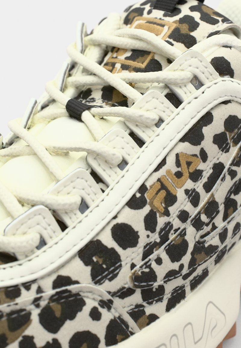 Weiße Sneaker mit einem Leopardenmuster in Schwarz und Braun. verfügen über dicke Schnürsenkel, einen gepolsterten Schaft und eine erhabene, strukturierte Sohle. Fila-Logo vorhanden.