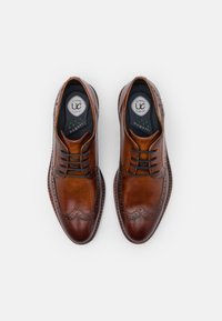 Chaussures habillées en cuir marron avec des détails en brogue, bout rond et fermeture à lacets noirs. Dotées de semelles intérieures rembourrées pour le confort.
