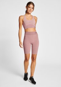 Ljusrosa sport-bh och cykelshorts-set tillverkat av fuktavledande tyg. Har en figurnära design med en slät textur och elastisk midja.
