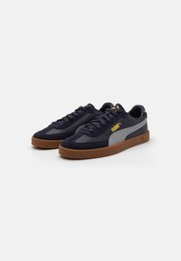 Navy blue suede and synthetic sneakers with gray accents and a gum rubber sole. Features lace-up design and logo on the side.