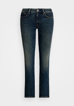Jean en denim bleu foncé avec une coupe droite, cinq poches et un léger délavage à l'avant. Fermeture à bouton et zip en argent.