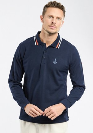 Polo à manches longues de couleur marine avec un col à trois boutons, un col rayé blanc et rouge, et un logo d'ancre brodé sur la poitrine. Matériau en coton.