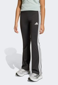 Crne atletske hlače s bijelim bočnim prugama, izrađene od rastezljivog materijala, s Adidas logotipom na lijevom bedru. Slim fit dizajn.