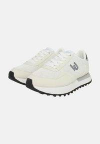 Sneaker in rete bianco e materiale sintetico con una suola grigia spessa, dotate di una suola nera testurizzata e un accento con logo grigio sui lati.