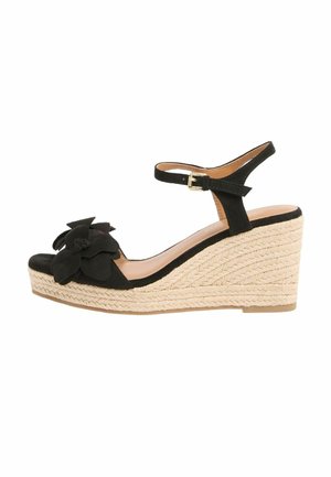 Sandale wedge negre din piele întoarsă cu platformă din iută împletită, baretă cu cataramă la gleznă și o mare decorare florală pe baretă la degetul piciorului.