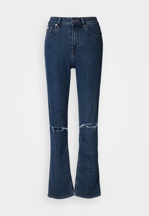 Tmavomodré rifle z denimu so zvonovým strihom, s vysokým pásom a detailom strhnutého kolena, vybavené bežným zapínaním na gombík a zips.