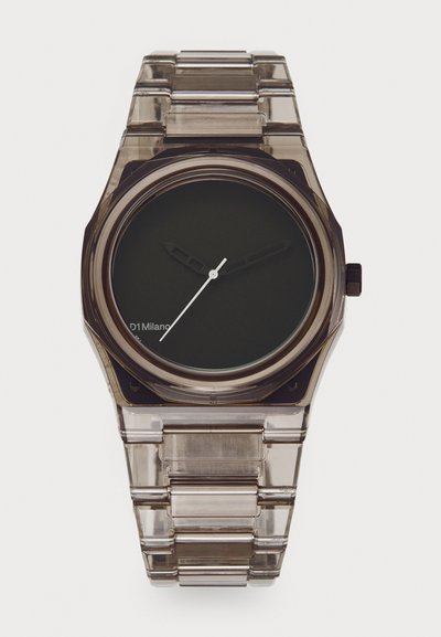 Transparent plastic watch with a dark green dial, silver hour and minute hands, and rectangular link bracelet. Logo displayed on the dial.
