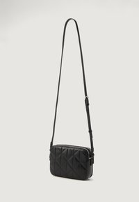 Černá prošívaná crossbody taška vyrobená z hladké umělé kůže. Má obdélníkový tvar, nastavitelné ramenní popruhy a stříbrný zip.