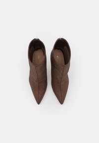 Brune ankelstøvler med tekstureret design, spids tå og lynlås lukning bagpå. Fremstillet af syntetisk materiale.